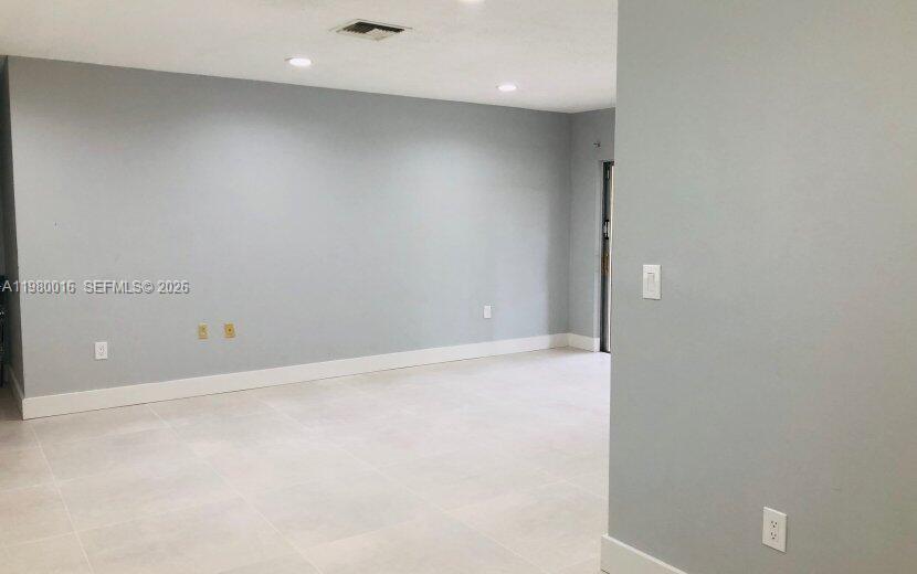 A spacious, empty room features light gray walls, white baseboards, and large light-colored floor tiles — 930 Benevento Ave # 930, Coral Gables FL 33146, CORAL GABLES, FL