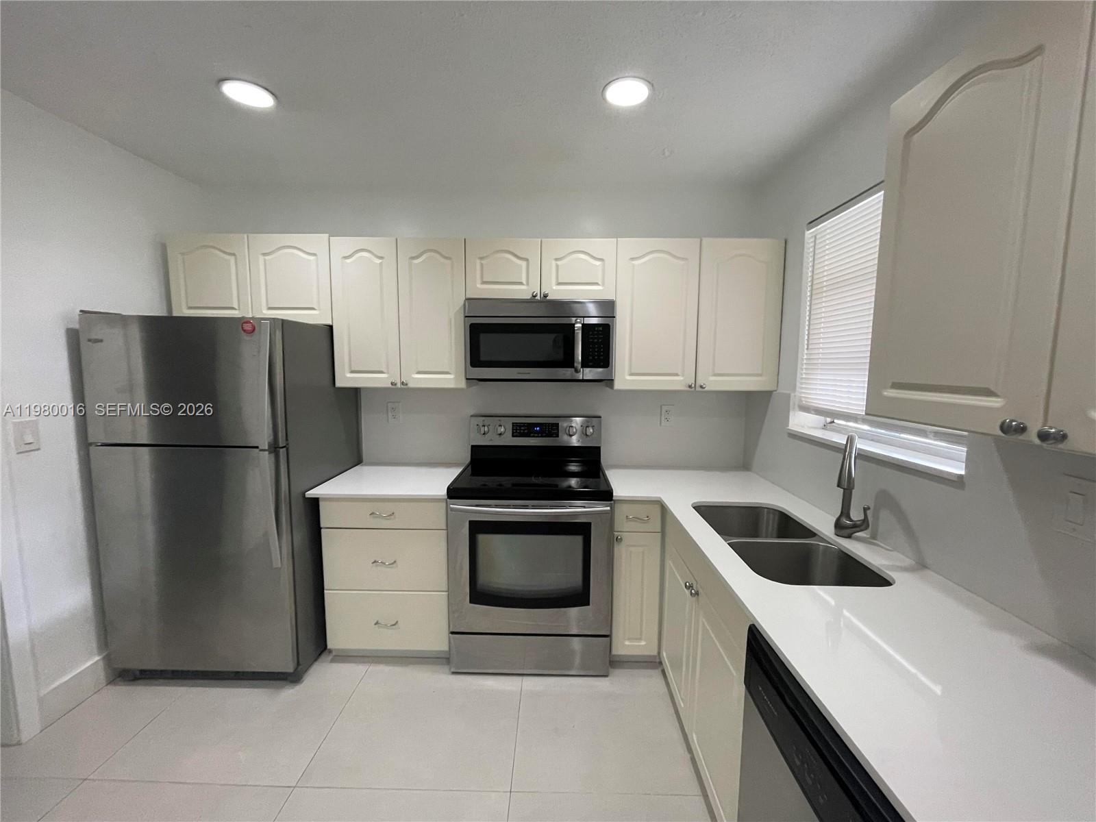 A kitchen features off-white cabinets, stainless steel appliances, and white countertops — 930 Benevento Ave # 930, Coral Gables FL 33146, CORAL GABLES, FL