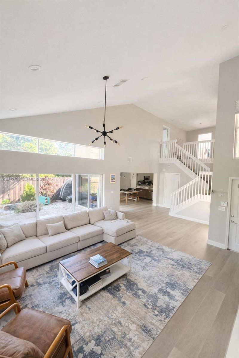 A spacious living room features a vaulted ceiling, a large sectional sofa, and a staircase — 1125 Butternut Ln, Hollywood FL 33019, HOLLYWOOD, FL