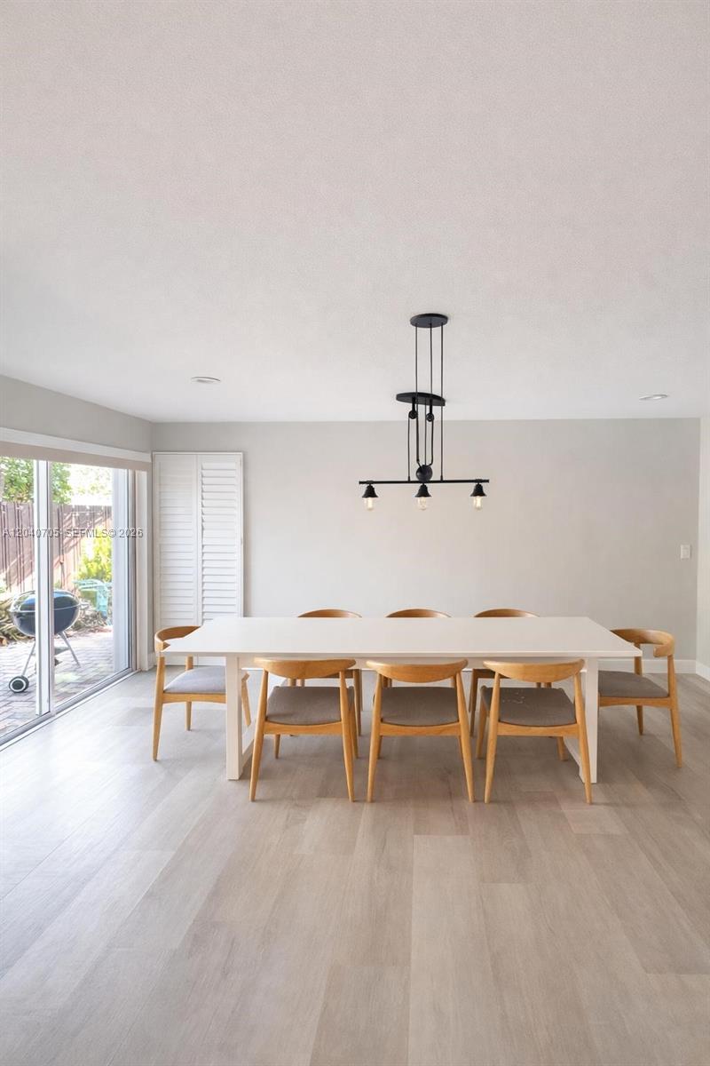 A dining room features a white table, wooden chairs, and a black pendant light fixture — 1125 Butternut Ln, Hollywood FL 33019, HOLLYWOOD, FL