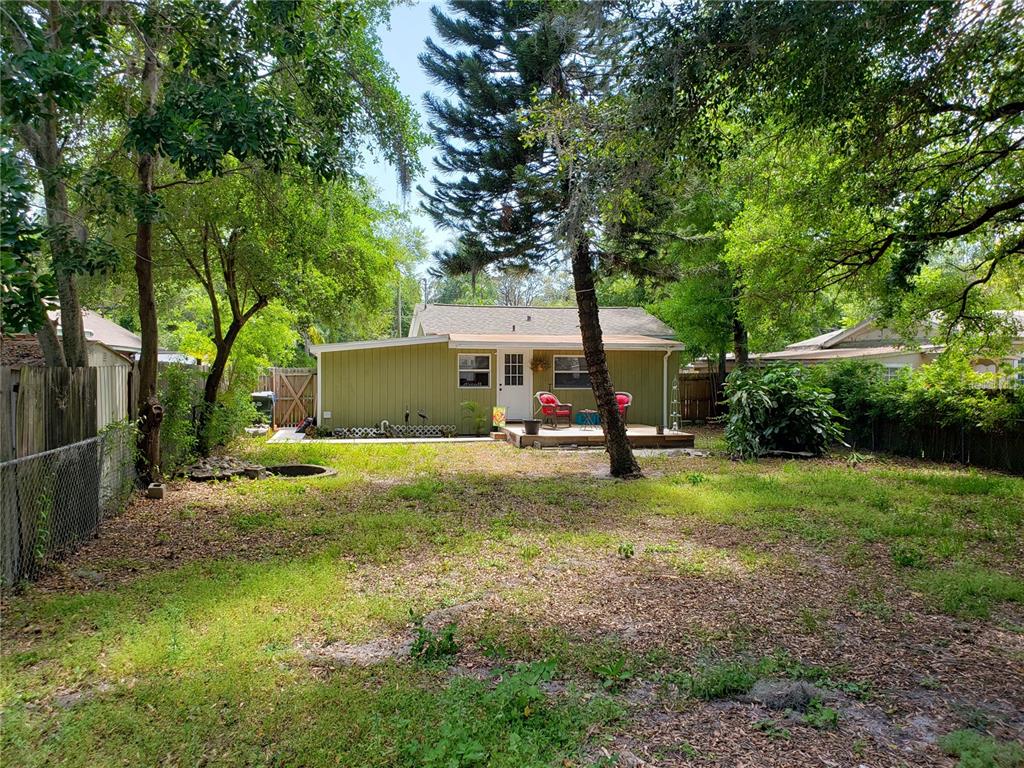 A backyard view of a single-story house with green siding and a wooden deck — 910 9TH AVENUE SW, LARGO, FL