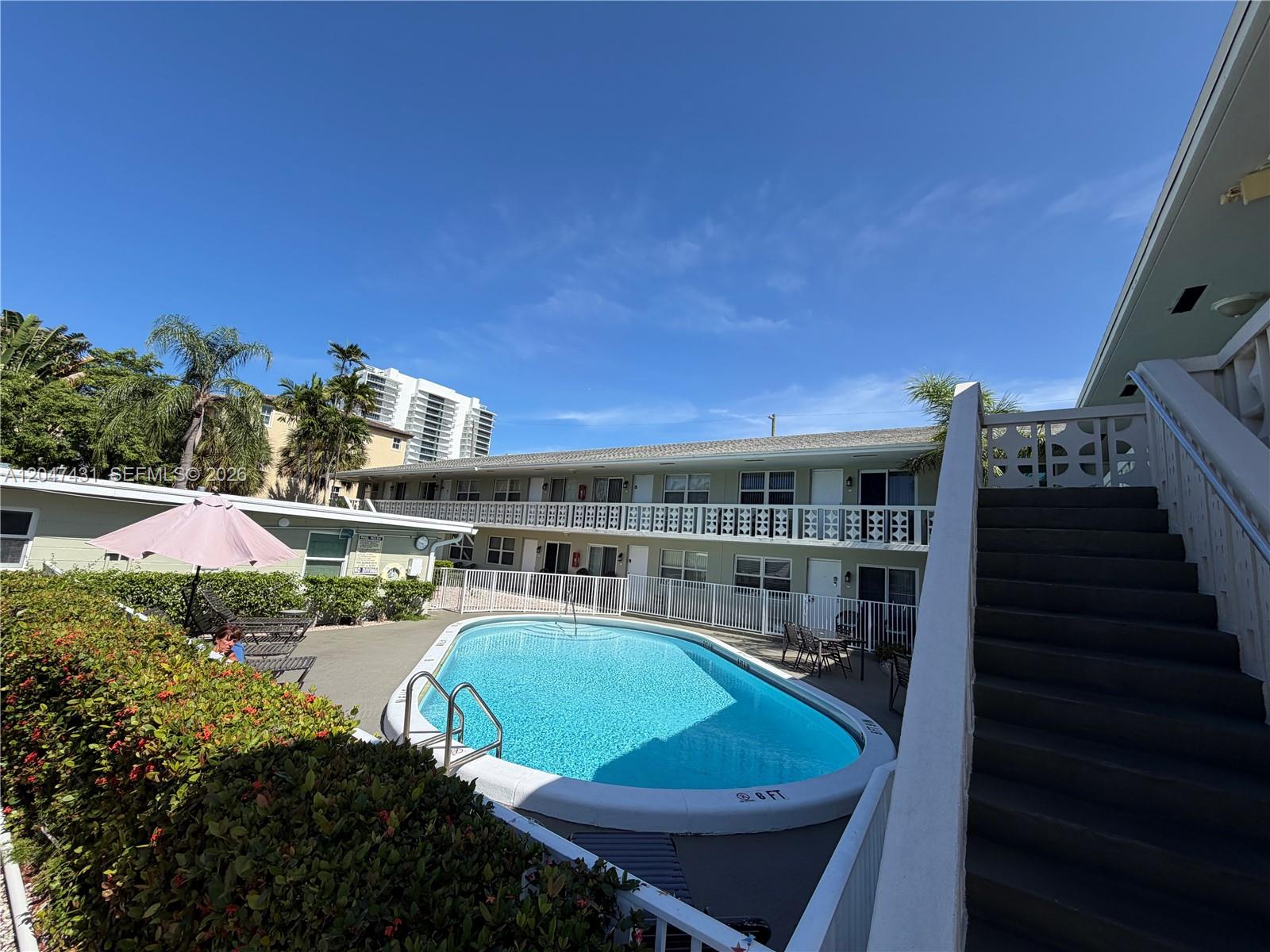 An outdoor swimming pool is situated in the courtyard of a two-story apartment complex — 3230 NE 13th St # 2, Pompano Beach FL 33062, POMPANO BEACH, FL