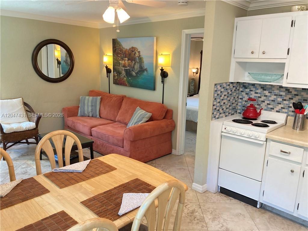 A living room and kitchen area feature a coral sofa, dining table, and white cabinetry — 3230 NE 13th St # 2, Pompano Beach FL 33062, POMPANO BEACH, FL