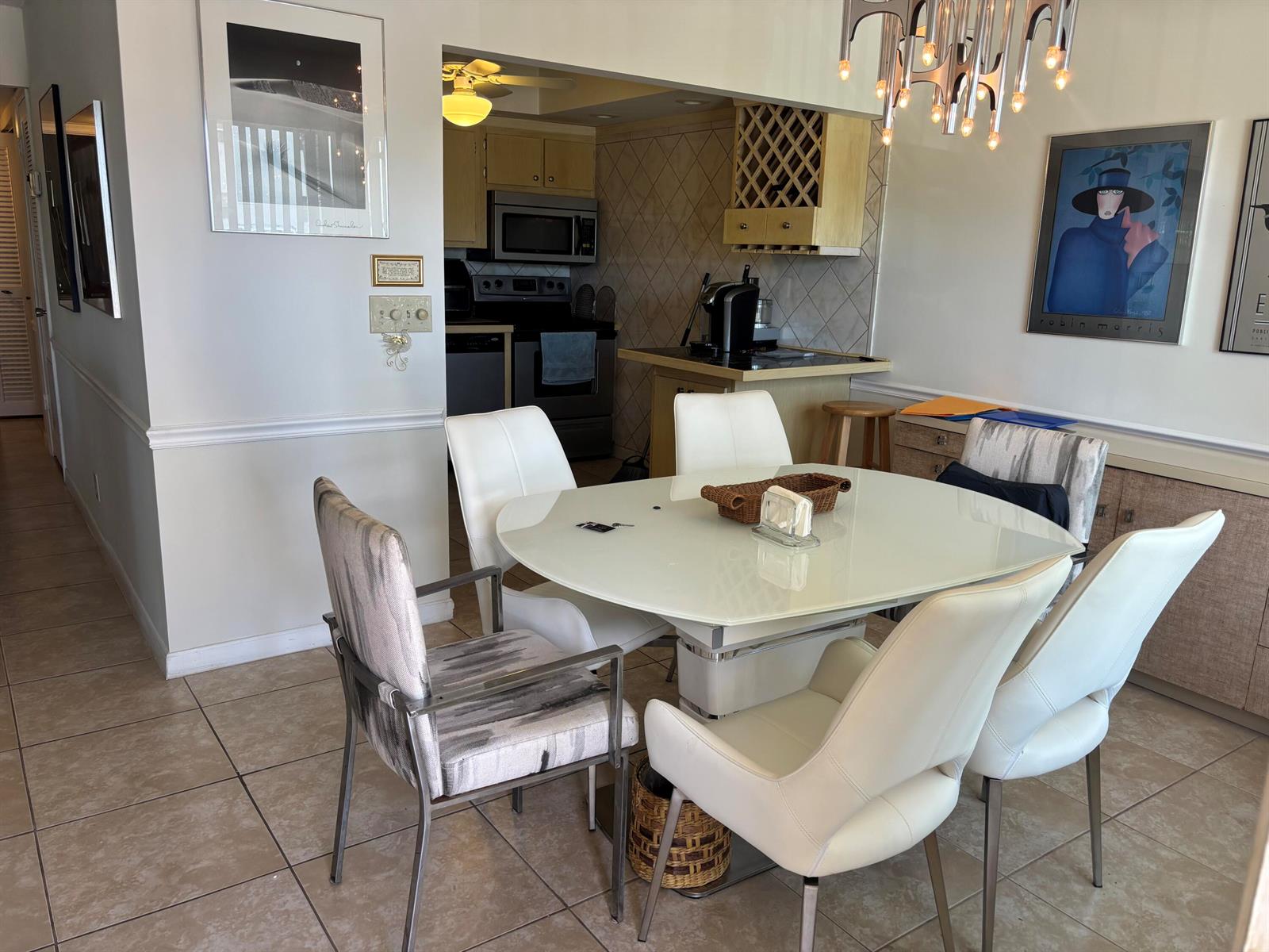 A dining area features a glass-topped table, mixed seating, and an adjacent kitchen with tile flooring — 105 E Wellington # 105, West Palm Beach FL 33417, WEST PALM BEACH, FL