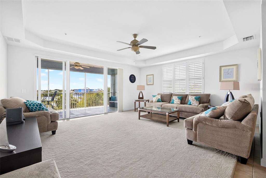 A living room with beige carpet, a ceiling fan, and sliding glass doors to a balcony — 2001 BAL HARBOR BOULEVARD UNIT 2308, PUNTA GORDA, FL