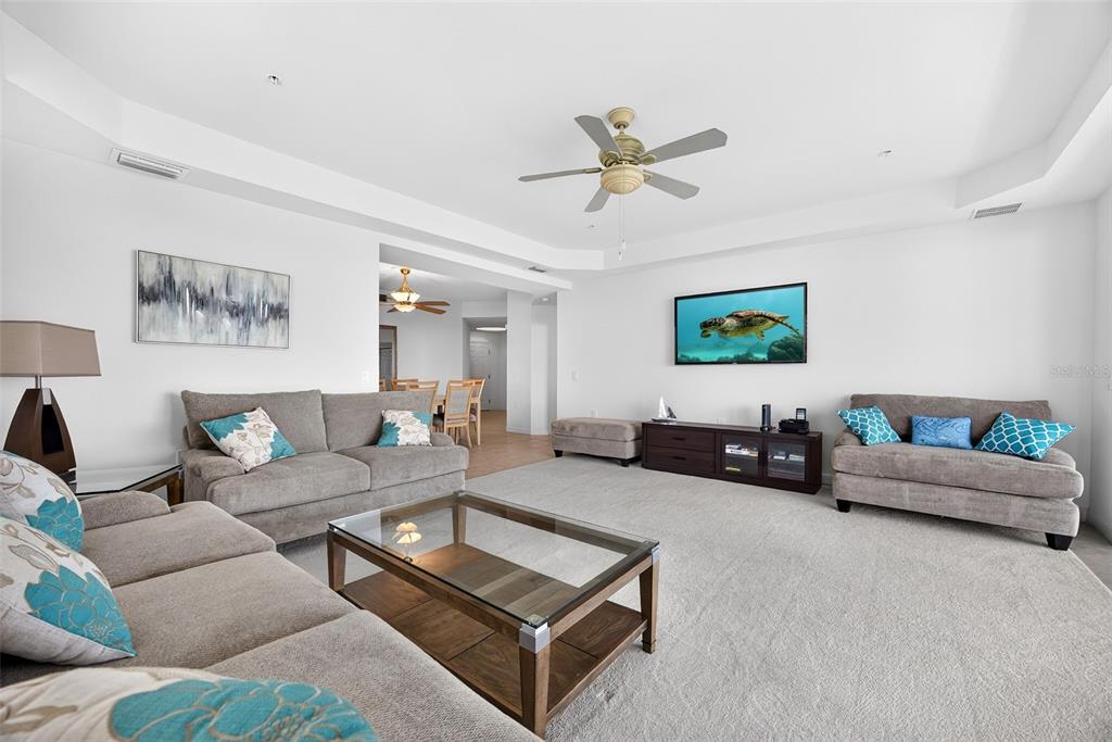 A living room features gray sofas, a glass-topped coffee table, and a wall-mounted television — 2001 BAL HARBOR BOULEVARD UNIT 2308, PUNTA GORDA, FL