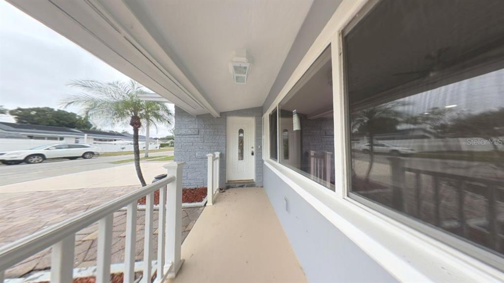 A covered front porch with a white railing, a white front door, and large windows — 8990 123RD WAY, SEMINOLE, FL