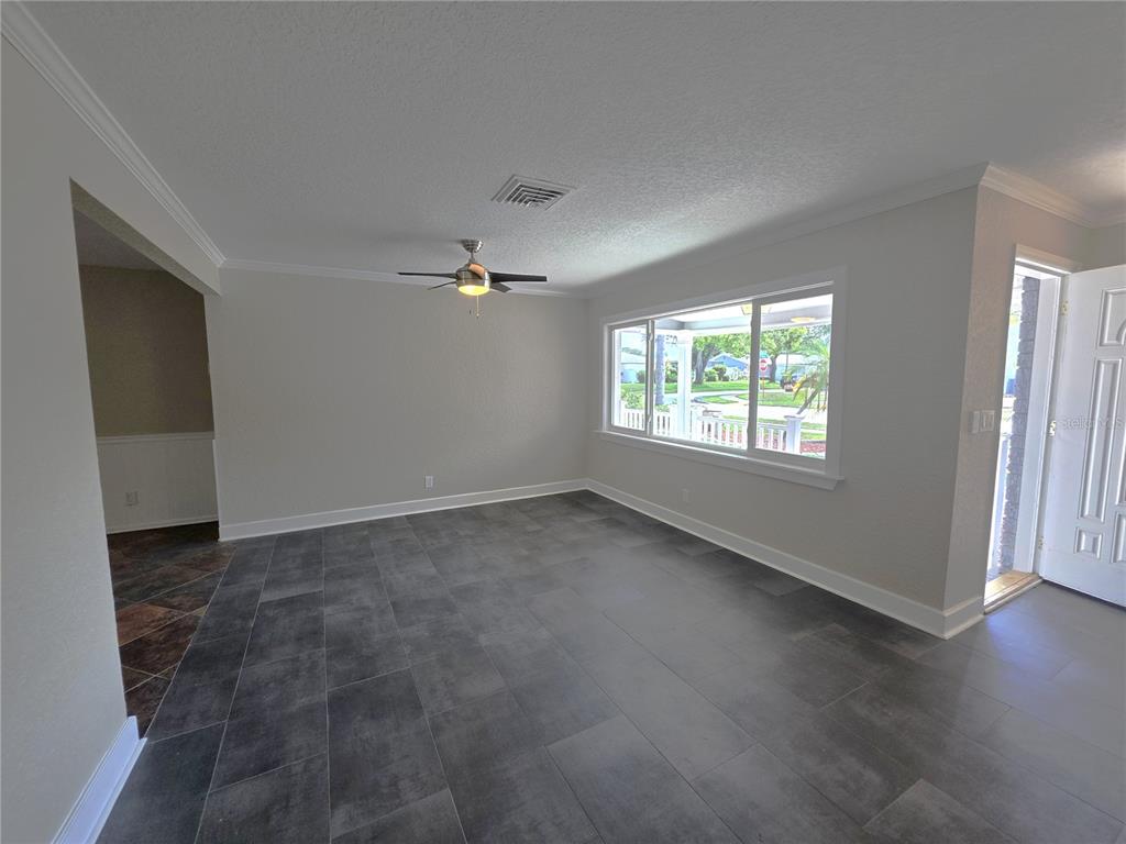 An empty room features gray tile flooring, a ceiling fan, and a large window — 8990 123RD WAY, SEMINOLE, FL