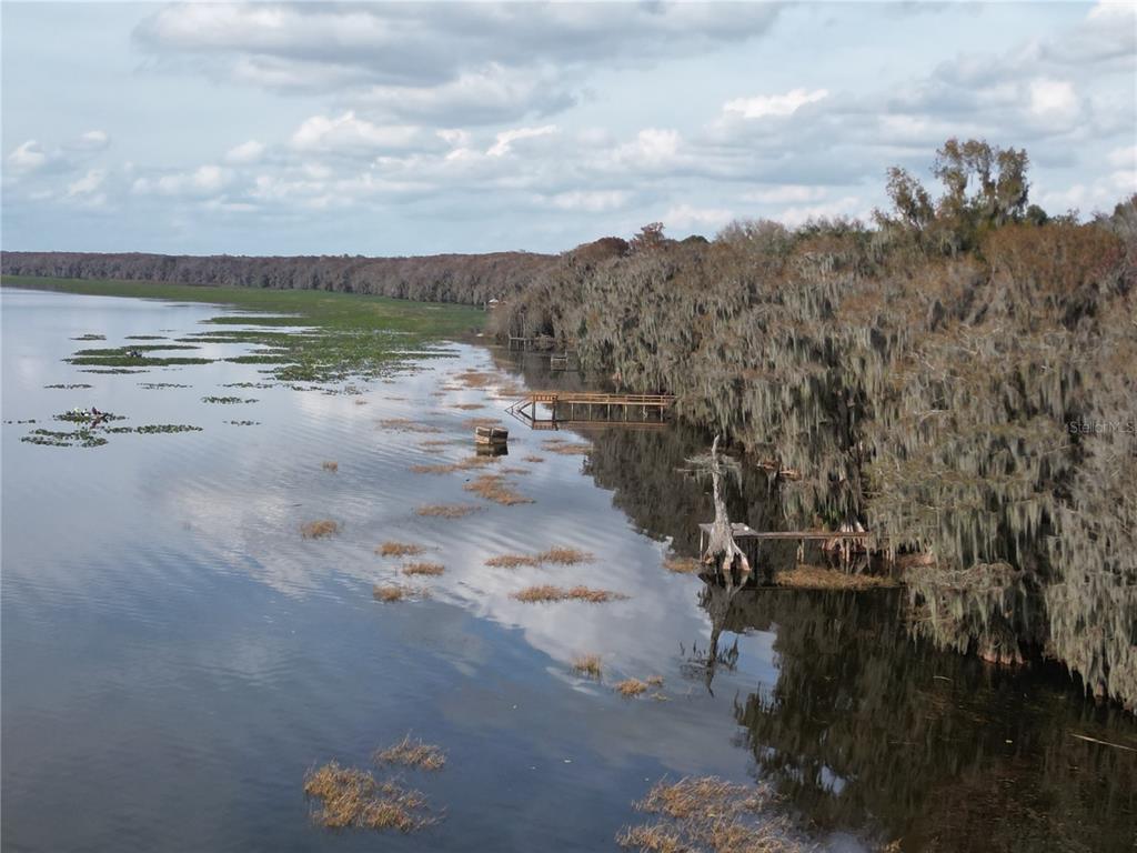 An aerial view of a lake shoreline with cypress trees, hanging moss, and wooden docks — 13813 SE 201ST TERRACE, HAWTHORNE, FL