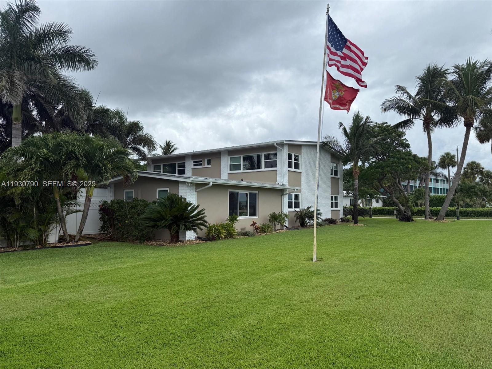 A two-story house with white brick accents and a flag pole stands on a lawn — 13549 S Indian River Dr, Jensen Beach FL 34957, JENSEN BEACH, FL