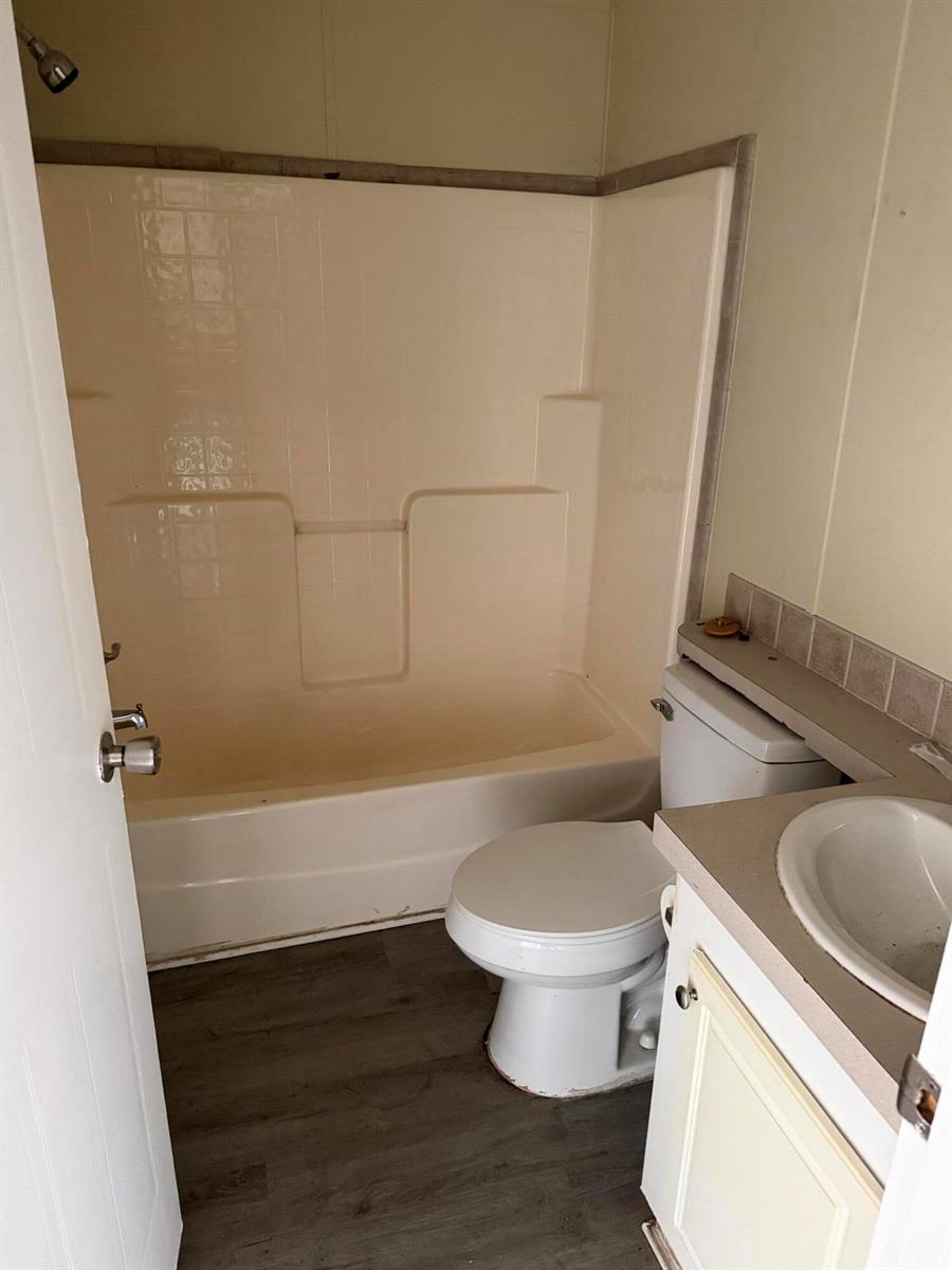 A small bathroom features a beige tub-shower surround, a white toilet, and a vanity — 8557 SW 18th Street, Davie FL 33324, DAVIE, FL
