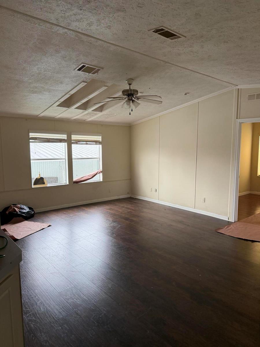 An empty living room features dark wood-look flooring, beige walls, and a ceiling fan — 8557 SW 18th Street, Davie FL 33324, DAVIE, FL