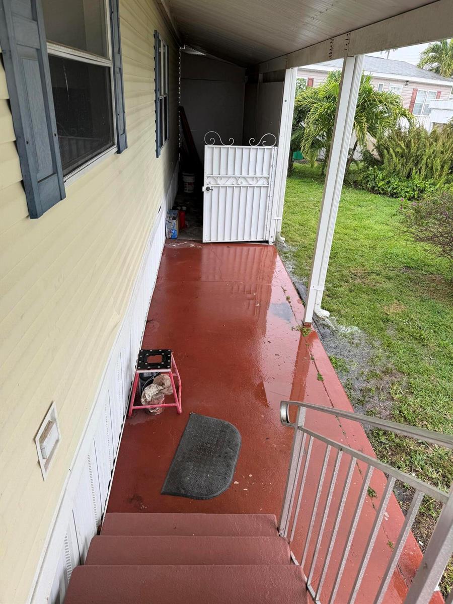 A covered porch with red painted flooring, metal railings, and a white gate — 8557 SW 18th Street, Davie FL 33324, DAVIE, FL