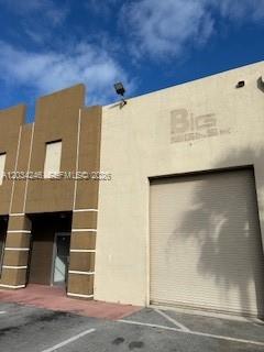 The exterior of a commercial building features a tan facade with a large roll-up door — HIALEAH GARDENS, FL