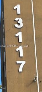 Large white house numbers are mounted vertically on a brown exterior wall — HIALEAH GARDENS, FL