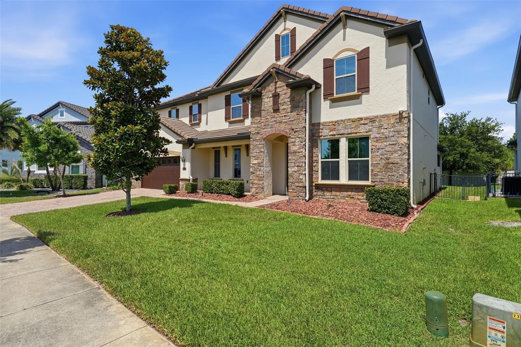 A two-story house with a stone facade, brown shutters, and a green lawn — 8210 LUDINGTON CIRCLE, ORLANDO, FL