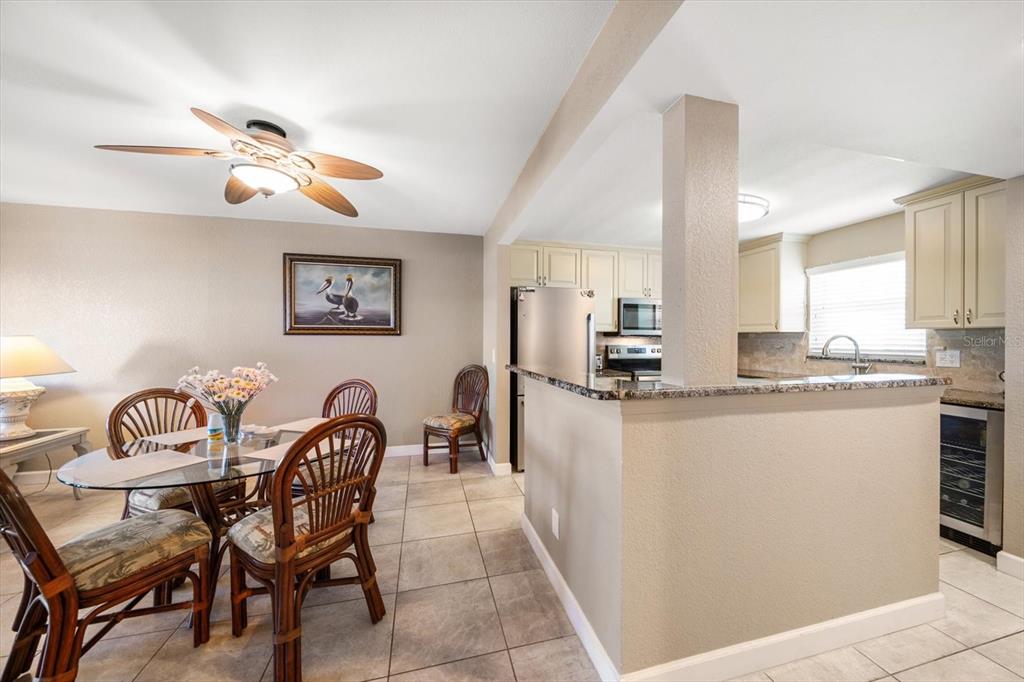 A dining area with a glass table and wicker chairs sits adjacent to a kitchen — 1230 GULF BOULEVARD UNIT 402, CLEARWATER BEACH, FL