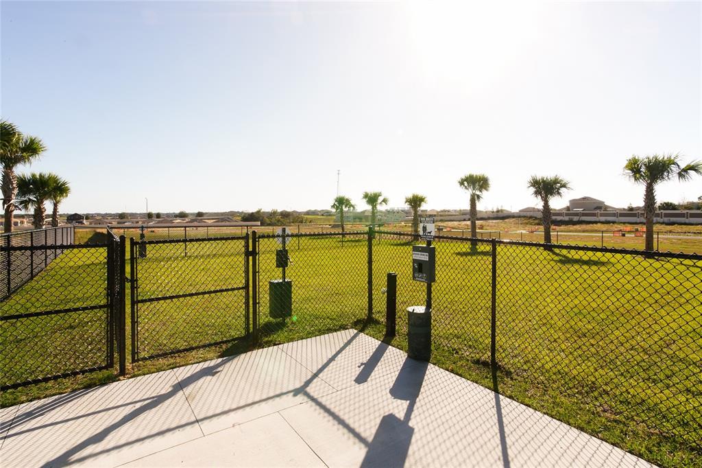 A fenced dog park features a concrete patio, waste station, and several palm trees — 1030 TWINS STREET, DAVENPORT, FL