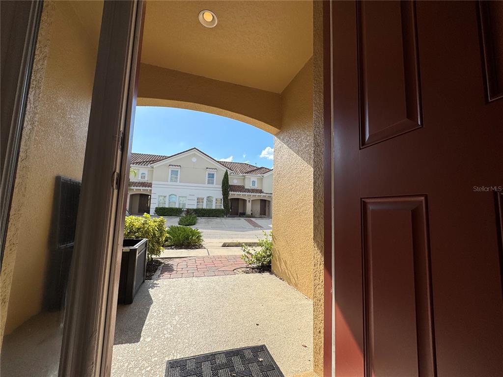 A view from an open doorway looking out onto a paved walkway and neighboring townhomes — 4678 TERRASONESTA DRIVE, DAVENPORT, FL