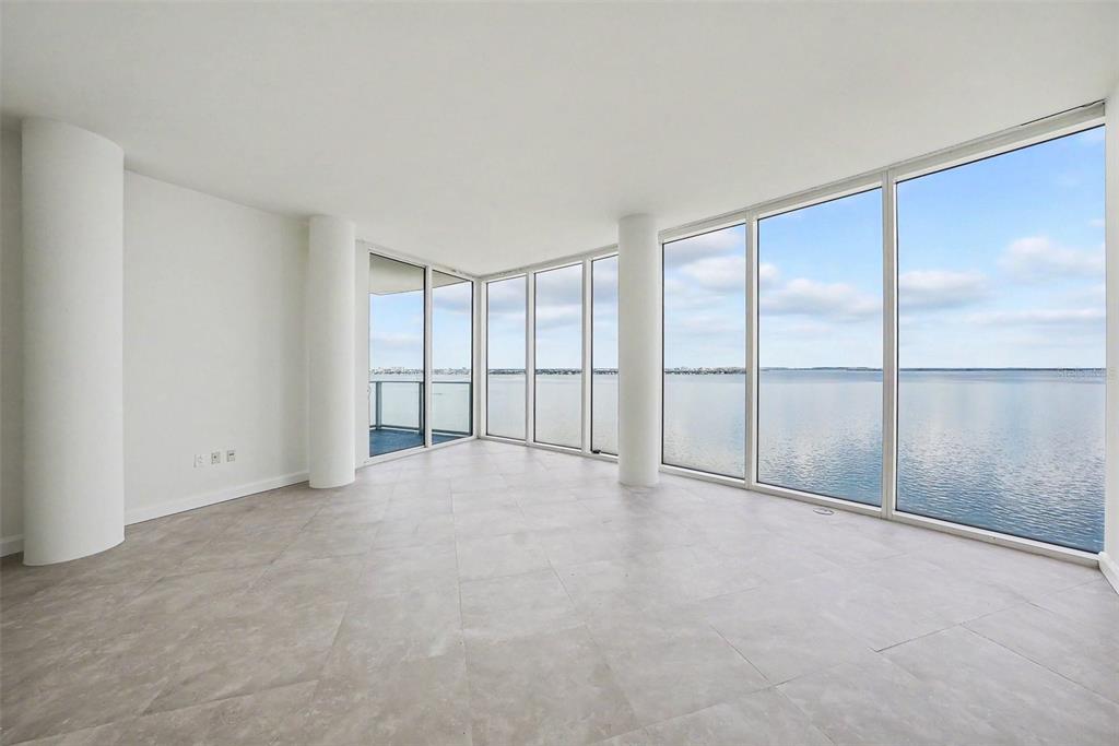 An empty room with light tile floors, white walls, structural columns, and floor-to-ceiling water views — 2900 W BAY TO BAY BOULEVARD UNIT 1502, TAMPA, FL