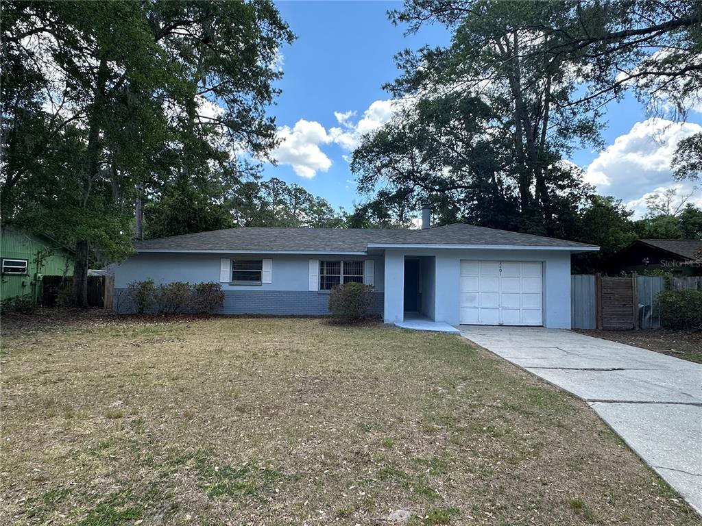 A single-story house with a light blue exterior, a one-car garage, and a concrete driveway — 4401 NW 20TH DRIVE, GAINESVILLE, FL