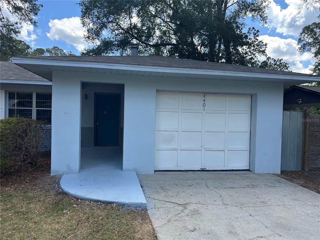 A light blue house exterior features a single-car garage and a recessed front entryway — 4401 NW 20TH DRIVE, GAINESVILLE, FL