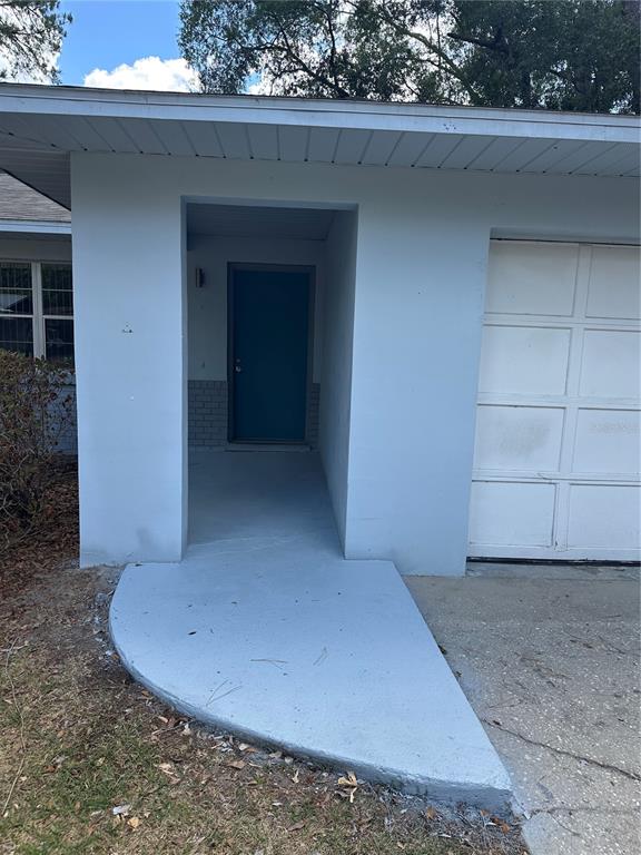 The exterior of a house features a blue front door, a concrete walkway, and a garage — 4401 NW 20TH DRIVE, GAINESVILLE, FL