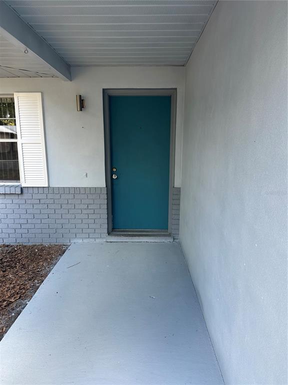 A teal front door is centered on a covered porch with gray brick and siding — 4401 NW 20TH DRIVE, GAINESVILLE, FL