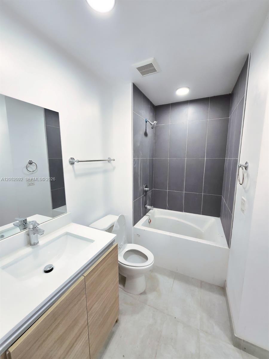 A bathroom features a vanity, a toilet, and a bathtub with gray tiled walls — 8106 NE 1st Ave # 13, Miami FL 33138, MIAMI, FL