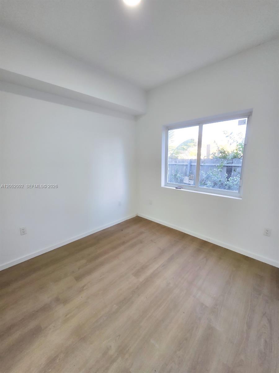 An empty bedroom features white walls, light wood-look flooring, and a single window — 8106 NE 1st Ave # 13, Miami FL 33138, MIAMI, FL