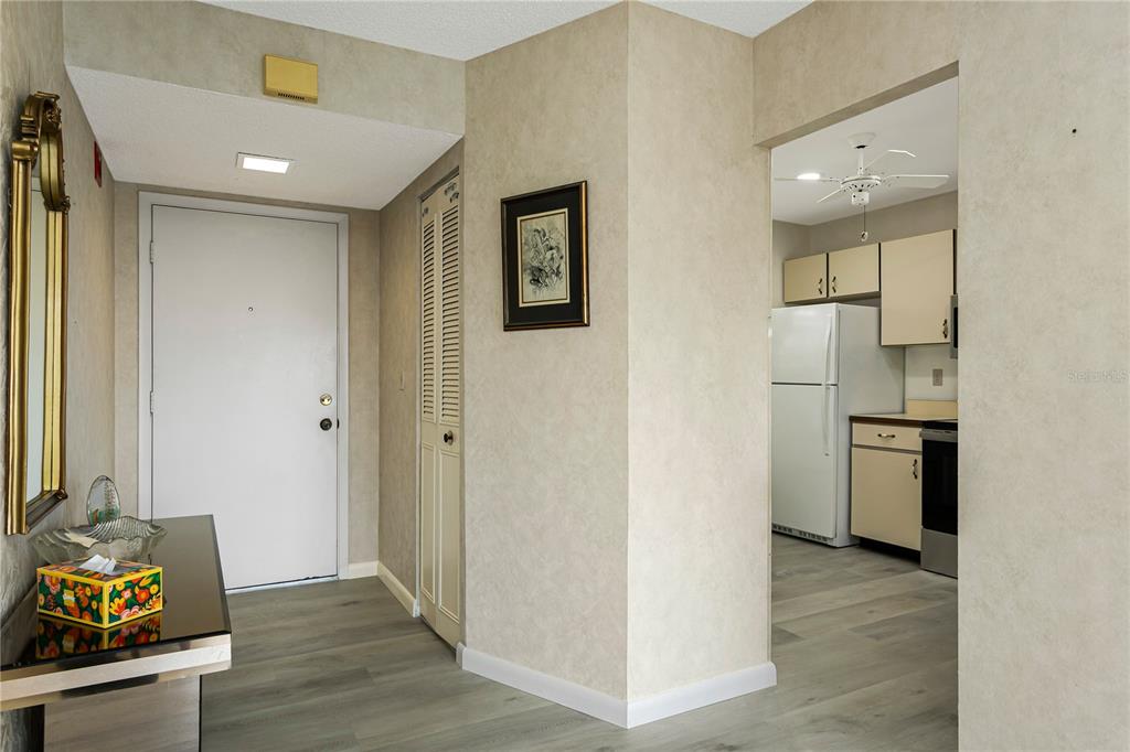 An entryway with light wood-look flooring leads into a kitchen with white appliances — 3640 IRONWOOD CIRCLE UNIT 503N, BRADENTON, FL