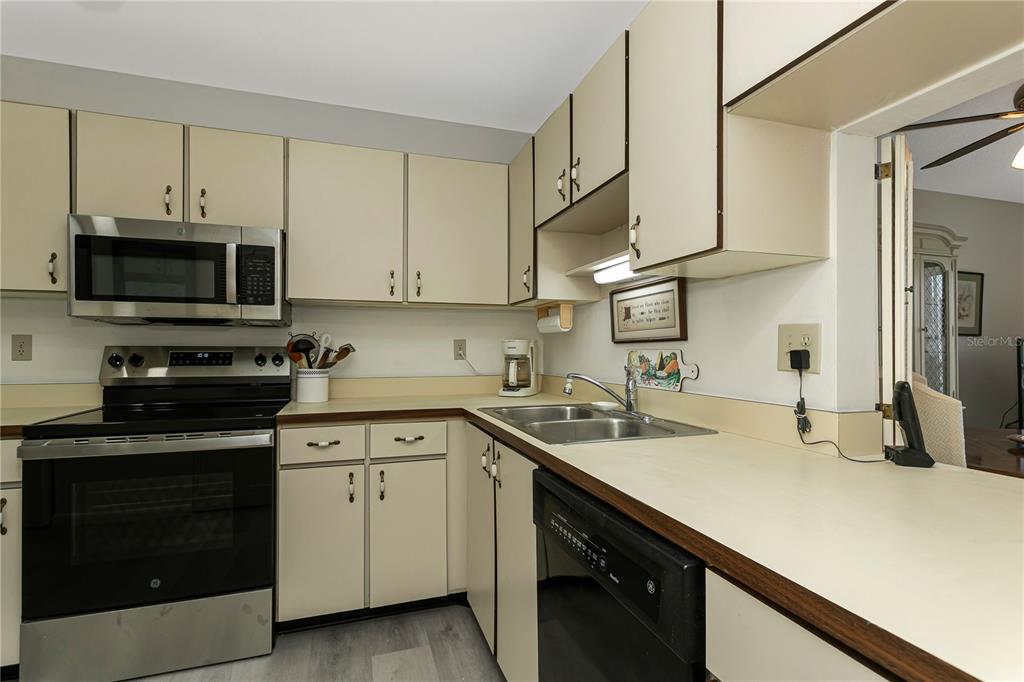 A kitchen features off-white cabinets, stainless steel appliances, and a laminate countertop with a sink — 3640 IRONWOOD CIRCLE UNIT 503N, BRADENTON, FL