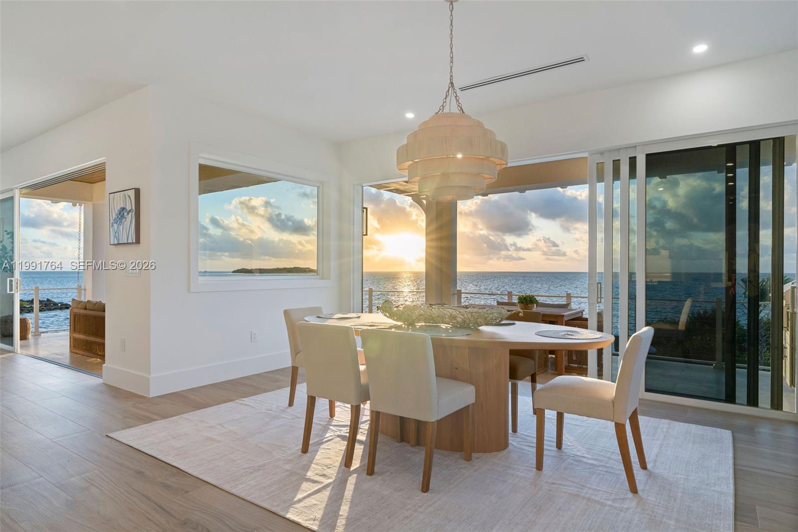 A dining room features an oval wooden table, light-colored chairs, and expansive ocean views — 1002 Snapper Ln, Key Largo FL 33037, KEY LARGO, FL