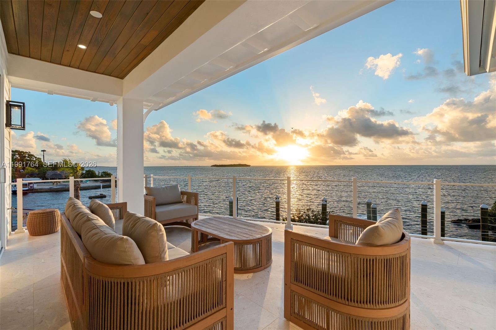 A covered patio features outdoor furniture overlooking the ocean at sunset — 1002 Snapper Ln, Key Largo FL 33037, KEY LARGO, FL
