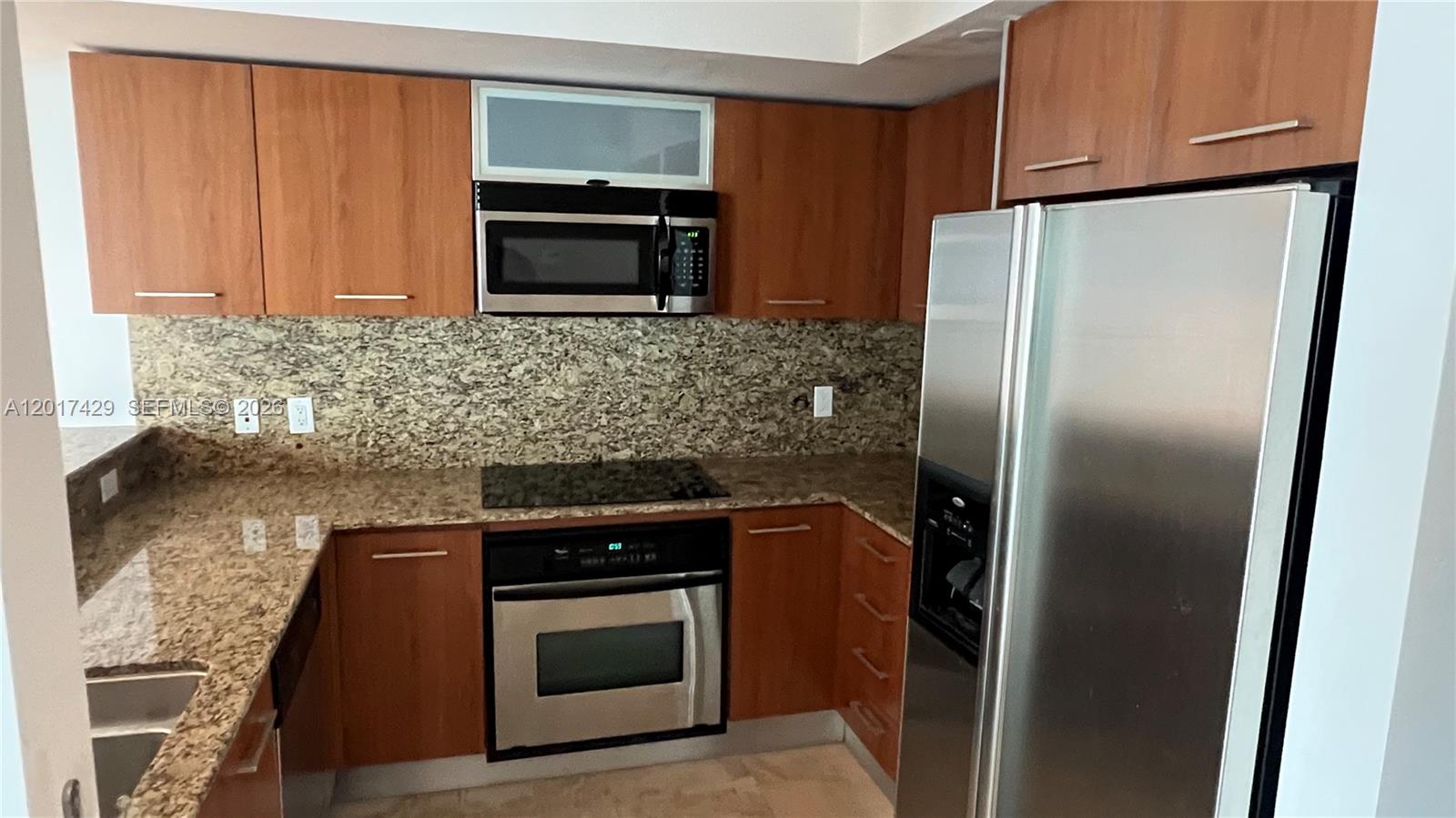 A kitchen features wood cabinets, granite countertops, stainless steel appliances, and a tiled backsplash — 9055 SW 73rd Ct # 2007, Miami FL 33156, MIAMI, FL