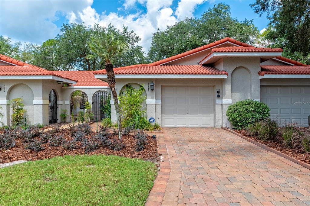 A single-story house with a red tile roof, beige stucco walls, and a brick driveway — 7720 CHAPELHILL DRIVE, ORLANDO, FL