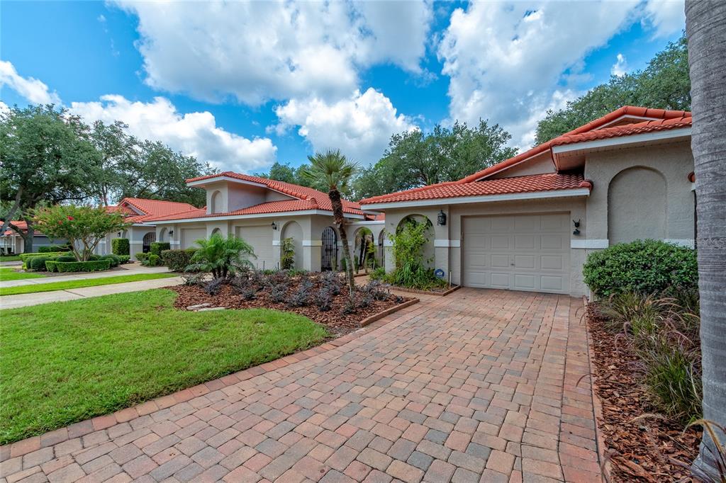A paved driveway leads to a tan house with a red tile roof and garage — 7720 CHAPELHILL DRIVE, ORLANDO, FL