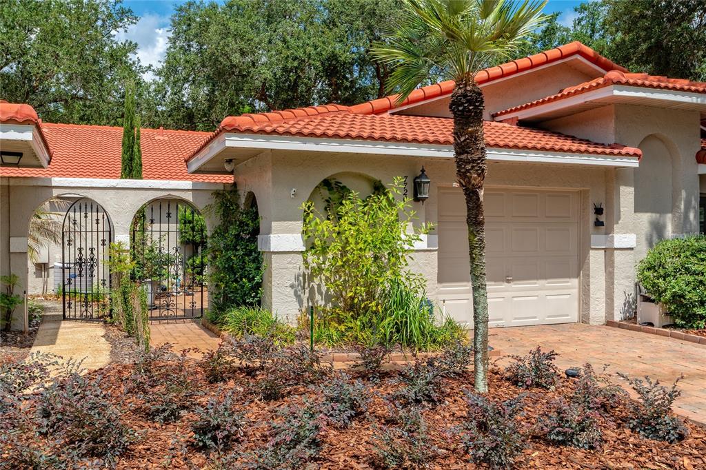 A house exterior features a red tile roof, a garage, and an arched gated entryway — 7720 CHAPELHILL DRIVE, ORLANDO, FL