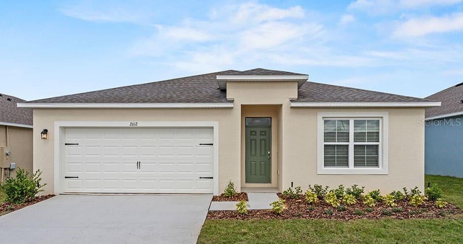 A single-story house with a beige stucco exterior, a two-car garage, and a green door — 2429 MAIDENS BLUFF AVENUE UNIT Cali, DAVENPORT, FL