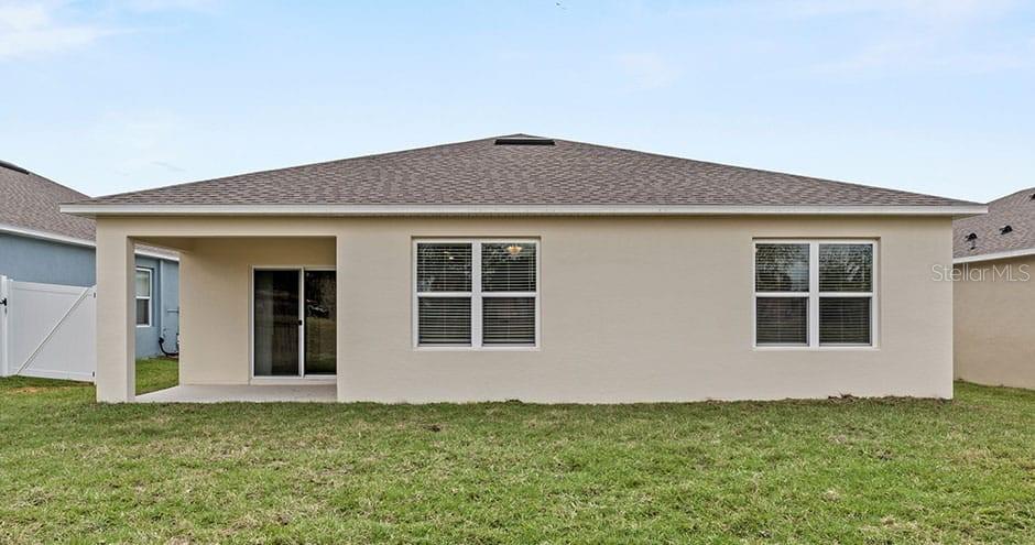 The rear exterior of a beige house features a covered patio and two windows — 2429 MAIDENS BLUFF AVENUE UNIT Cali, DAVENPORT, FL