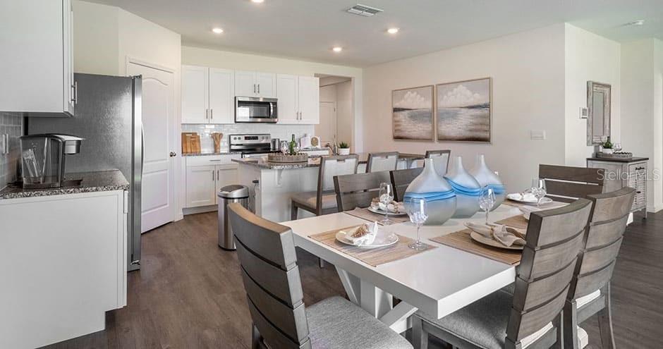 A kitchen and dining area with white cabinets, stainless steel appliances, and a wooden table — 2429 MAIDENS BLUFF AVENUE UNIT Cali, DAVENPORT, FL