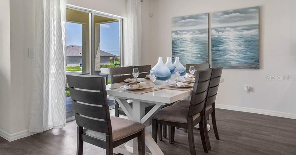 A dining room features a white table, six dark chairs, and two coastal-themed wall paintings — 2429 MAIDENS BLUFF AVENUE UNIT Cali, DAVENPORT, FL