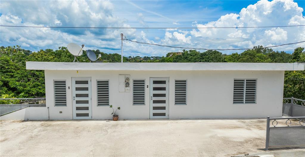 A white, single-story building with two numbered doors and louvered windows sits on a concrete patio — Km 0.1 CARR 412 INT, RINCON, PR