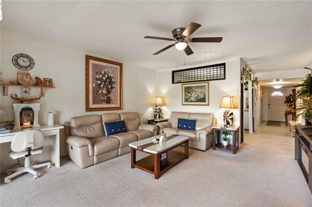 A living room features beige leather sofas, a coffee table, and a desk area — 7623 RADCLIFFE CIRCLE UNIT 211A, PORT RICHEY, FL
