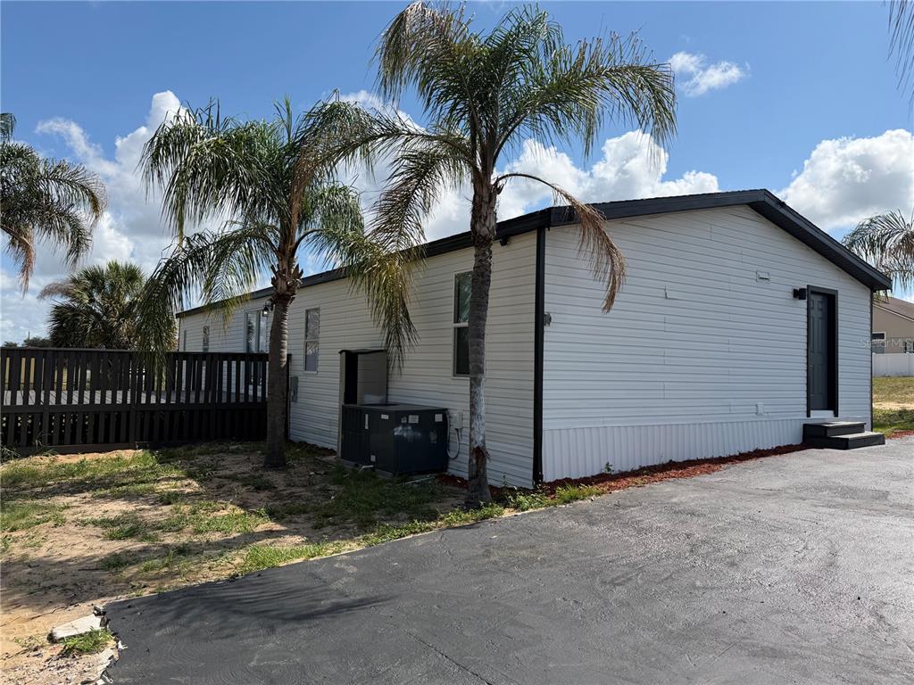 A white mobile home with a dark roof, palm trees, and an asphalt driveway — 3609 FDC GROVE ROAD, DAVENPORT, FL