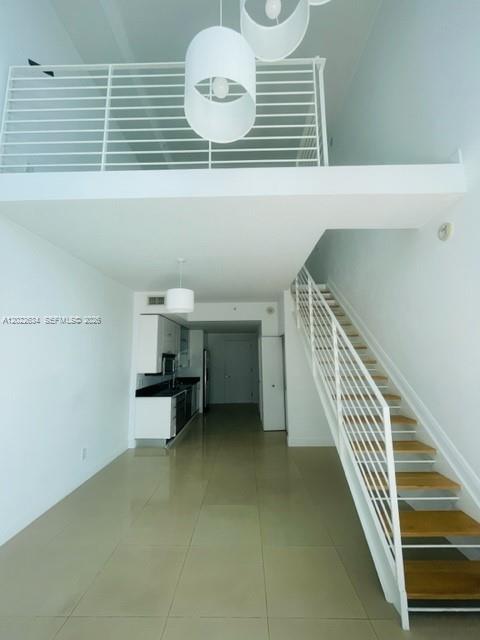 A modern loft apartment features a white staircase, tile flooring, and a mezzanine level — 60 SW 13th St # 3622, Miami FL 33130, MIAMI, FL