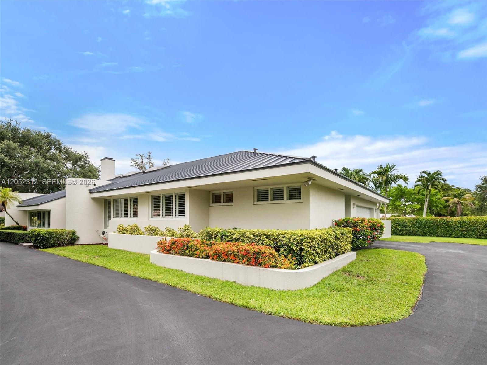 A single-story house with a metal roof and a curved driveway sits behind landscaped planters — 10321 SW 89th Ave, Miami FL 33176, MIAMI, FL