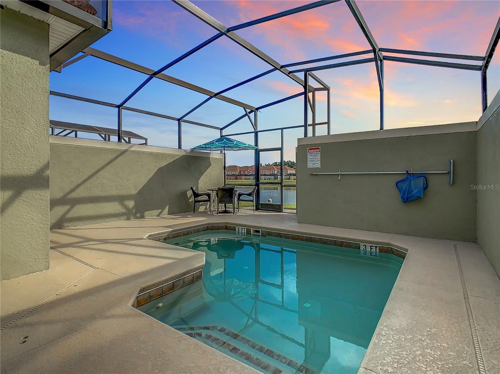 A screened-in pool area features a small swimming pool and a patio with outdoor furniture — 3039 BEACH PALM AVENUE, KISSIMMEE, FL