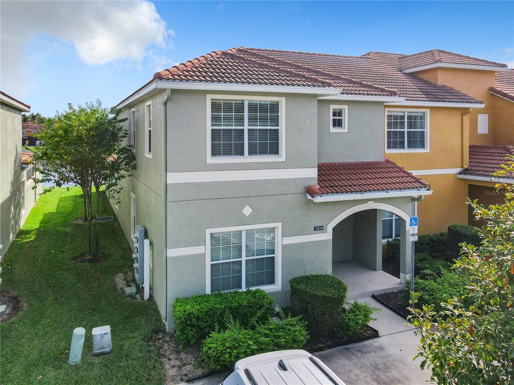 A two-story townhouse with a light green stucco exterior and a tiled roof — 3039 BEACH PALM AVENUE, KISSIMMEE, FL