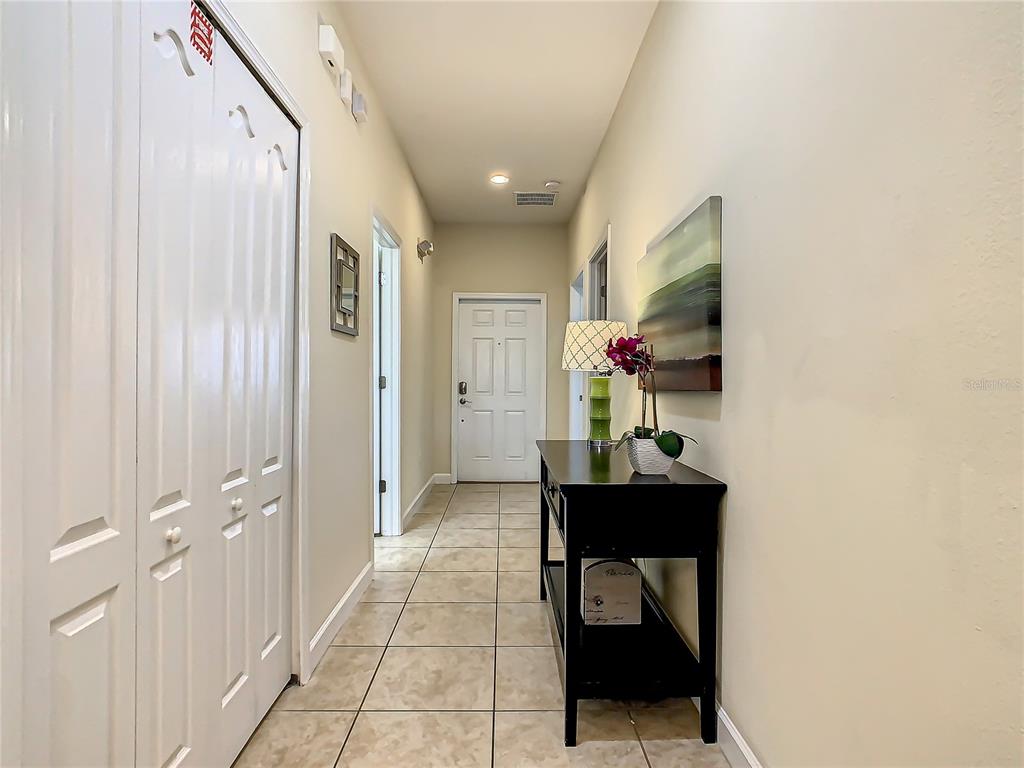 A hallway with tile flooring, a white door, and a black console table with decor — 3039 BEACH PALM AVENUE, KISSIMMEE, FL